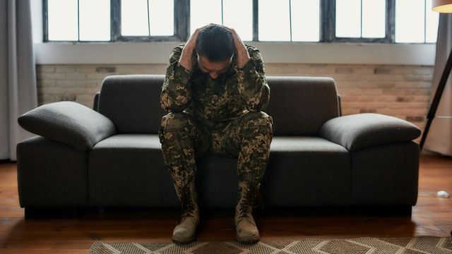 A veteran with PTSD sits on a sofa.  