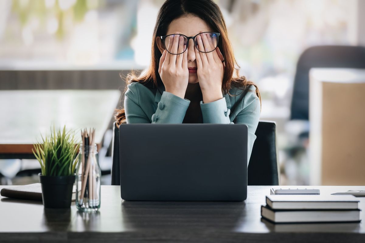 A person holding their head in their hands, looking tired.
