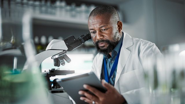A scientist looking at a tablet screen. 