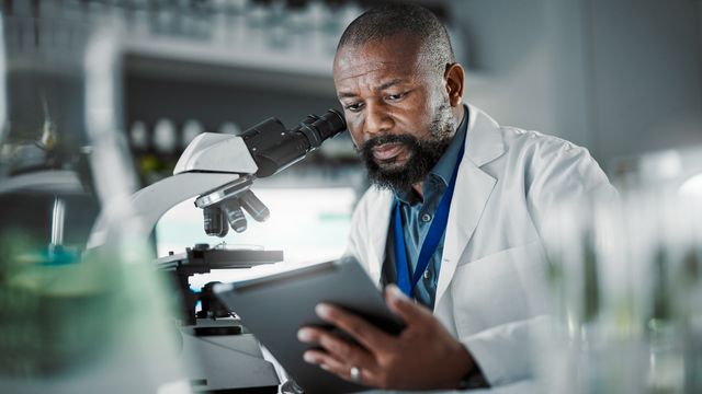 A scientist looking at a tablet screen. 