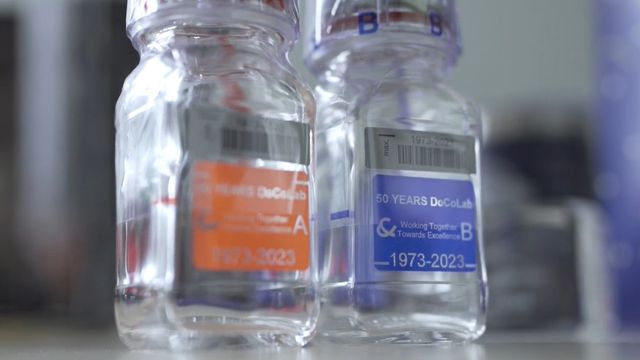 Two reagent bottles standing side-by-side with labels commemorating 50 years of DoCoLab. 
